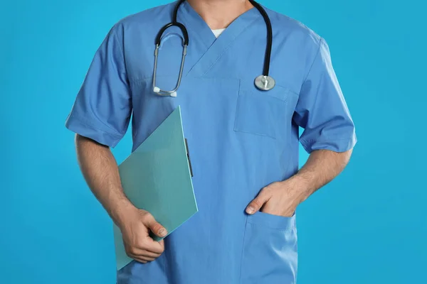 Dokter met klembord op blauwe achtergrond, close-up — Stockfoto