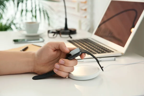 Homem tomando smartwatch do carregador sem fio na mesa branca, clos — Fotografia de Stock