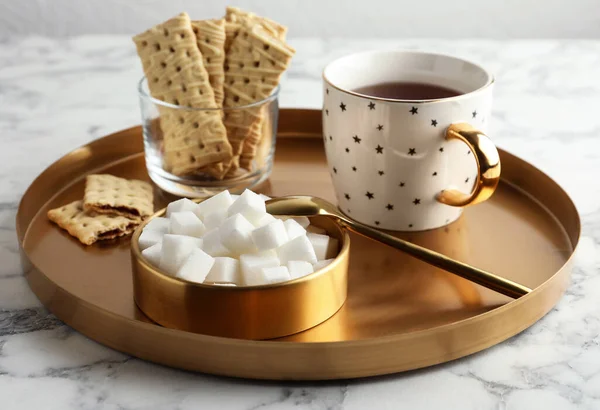 Finomított kockacukor tálban és aromás tea fehér márványlapon — Stock Fotó