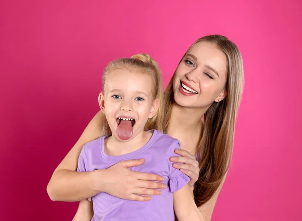 Mãe feliz e filha pequena no fundo rosa — Fotografia de Stock