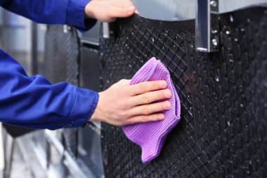 Worker wiping automobile floor mat at car wash, closeup