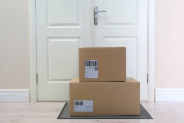 Kapının yanındaki halıda karton kutular. Paket teslimat servisi