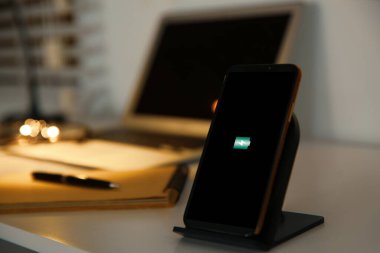 Masada kablosuz şarj aleti olan bir cep telefonu. Modern işyeri ac
