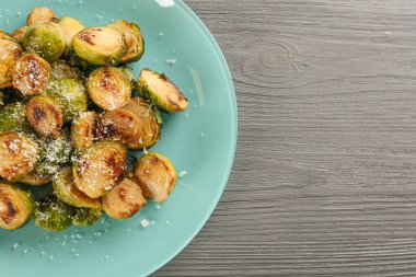 Grinin üstünde rendelenmiş peynirle fırında pişmiş Brüksel lahanası.
