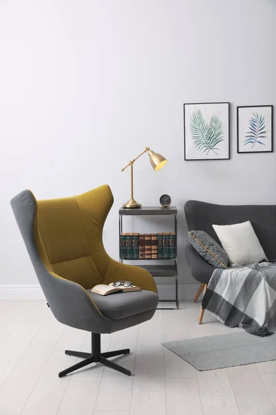 Стильный интерьер комнаты с удобным креслом, диваном и краской — стоковое фото