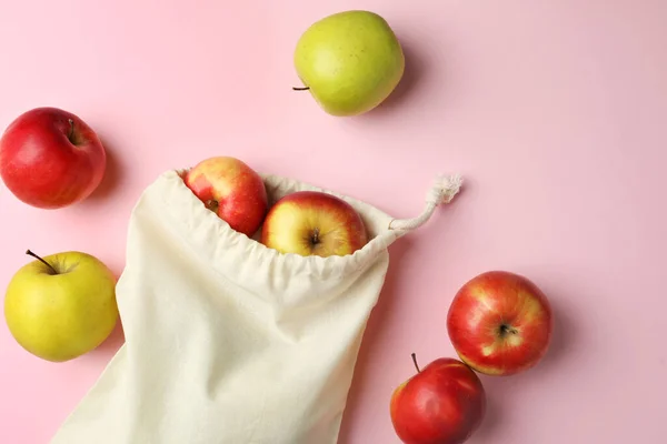 Cotton eco bag and apples on pink background, flat lay