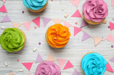 Colorful birthday cupcakes on white wooden table, flat lay
