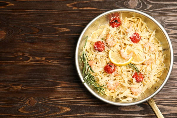 Delicious pasta with shrimps on wooden table, top view. Space for text