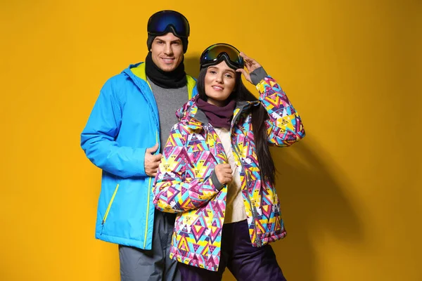 Cuplu purtând haine elegante de iarnă pe fundal galben — Fotografie, imagine de stoc