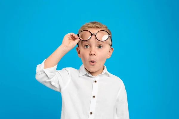 Retrato de menino bonito com óculos no fundo azul claro — Fotografia de Stock