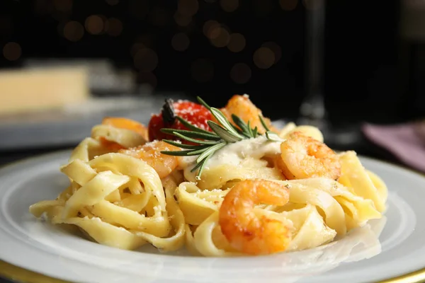 Delicious pasta with shrimps on black background, closeup