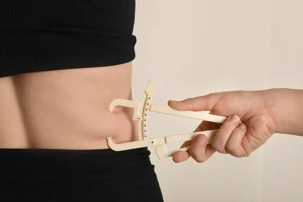 Nutrizionista misurazione strato di grasso corporeo della donna con pinza su essere — Foto Stock