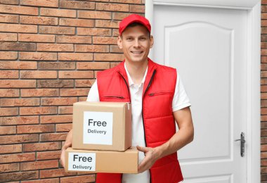 Çıkartmalı paketler taşıyan kurye. İçeriye ücretsiz teslimat.
