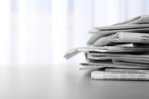 Pile of newspapers on grey table, space for text. Journalist\'s work