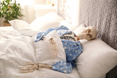 Pijamalı insan iskeleti yatağın içinde uzanıyor.