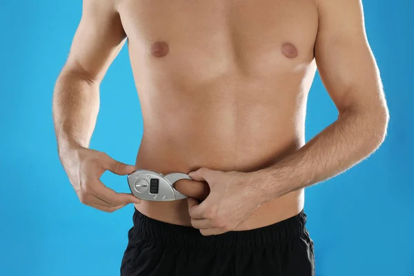 ライトブルーの背景にデジタルキャリパーで体脂肪層を測定男 クローズアップ 栄養士の道具 — ストック写真
