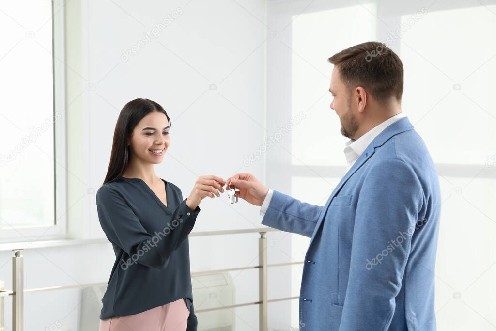 Real estate agent giving key to client in new apartment