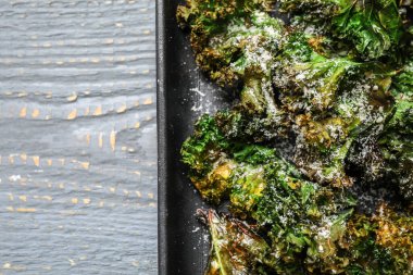 Açık gri ahşap masa üzerinde lezzetli lahana cipsleri, üst manzara. Metin için boşluk