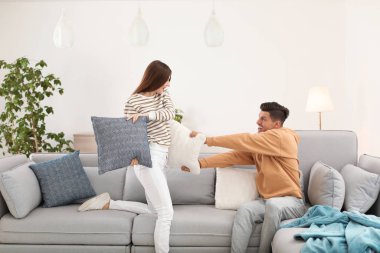 Mutlu çift oturma odasında yastık savaşı yapıyor.