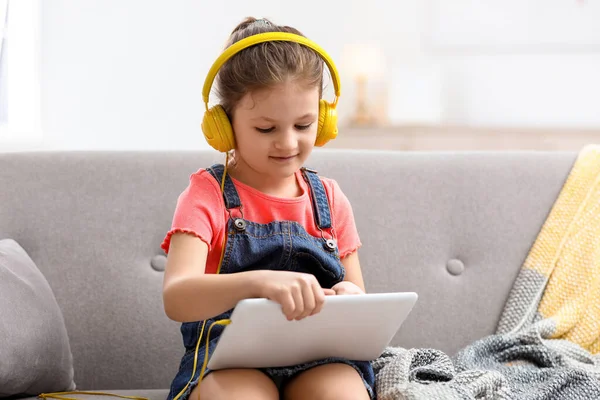 Schattig Klein Meisje Met Hoofdtelefoon Tablet Bank Thuis — Stockfoto