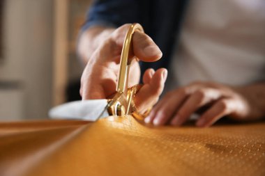 Atölyede deriyi makasla kesen adam, yakın plan.