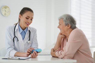 Doktor, ofisteki kıdemli hastaya ilaç veriyor.