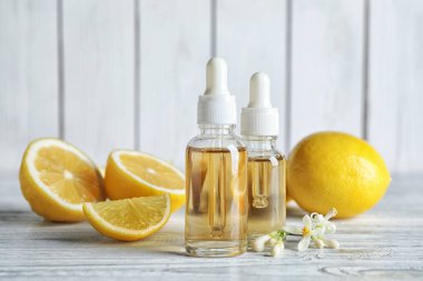 Beyaz ahşap masa üzerinde turunç, çiçek ve limon şişeleri.