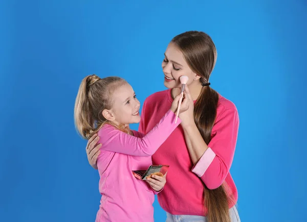 Feliz Hija Aplicando Polvo Cara Madre Sobre Fondo Azul — Foto de Stock