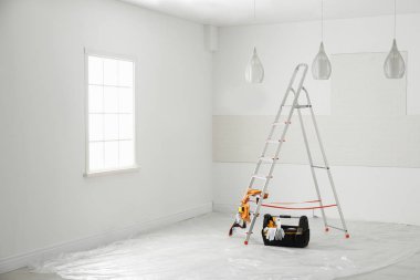 Stepladder and different tools near wall in room. Interior renovation