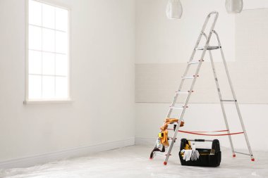Stepladder and different tools near wall in room. Interior renovation