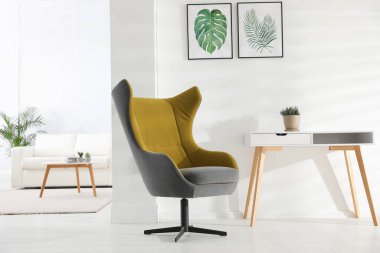 Rahat koltuk ve tropikal yaprak resimleriyle süslü bir oda.