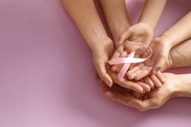 Renkli arka planda pembe kurdele tutan aile, yazı için yeri olan üst manzara. Göğüs kanseri farkındalığı
