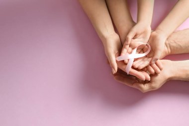 Renkli arka planda pembe kurdele tutan aile, yazı için yeri olan üst manzara. Göğüs kanseri farkındalığı