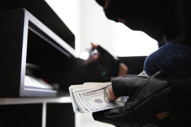 Thief taking money out of steel safe indoors, closeup