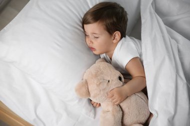 Evde oyuncakla uyuyan şirin bir bebek. Yatma zamanı.