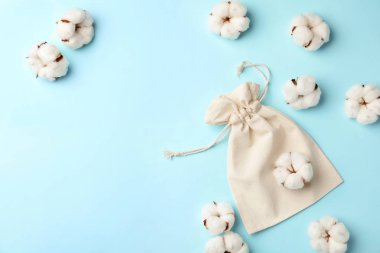 Pamuk eko çanta ve açık mavi arka planda çiçekler, düz bir zemin. Metin için boşluk