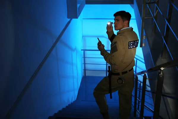 暗い部屋の階段に設置された懐中電灯やポータブルラジオ付きの専門的なセキュリティガード — ストック写真