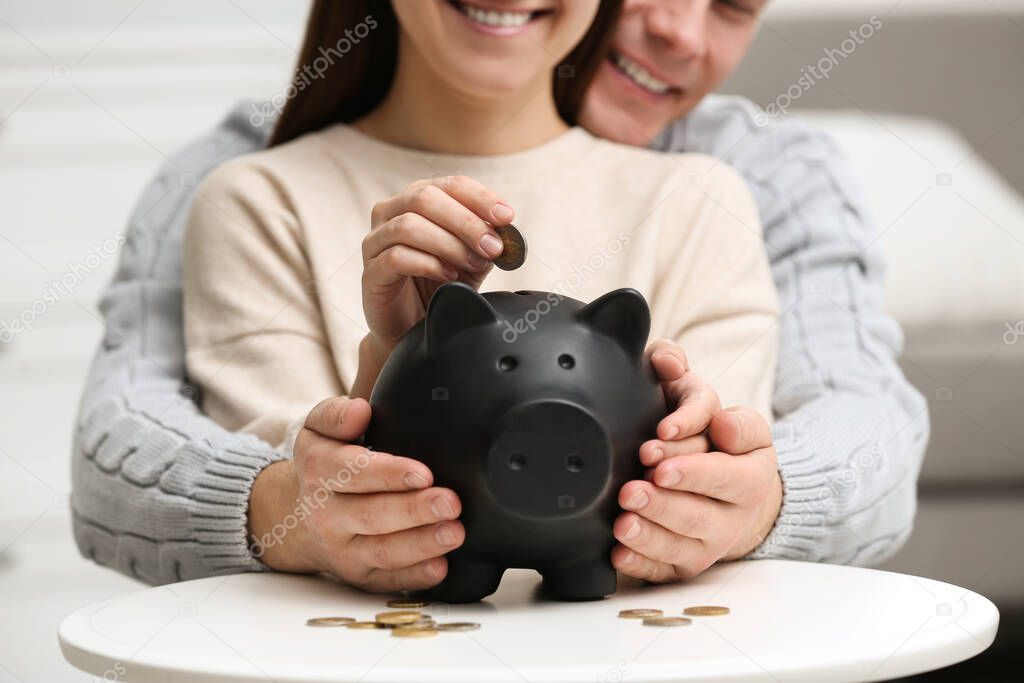 Couple with piggy bank at white table, closeup