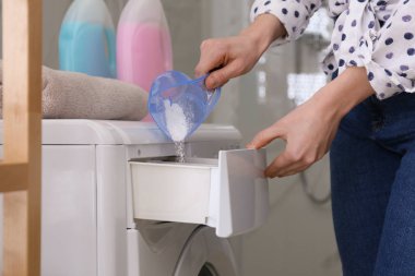 Çamaşır deterjanı banyodaki çamaşır makinesinin çekmecesine dolduran kadın.
