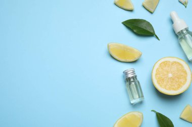 Flat lay composition with bottles of citrus essential oil on light blue background. Space for text