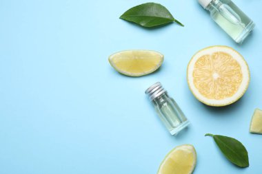 Flat lay composition with bottles of citrus essential oil on light blue background. Space for text