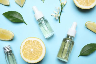 Flat lay composition with bottles of citrus essential oil on light blue background