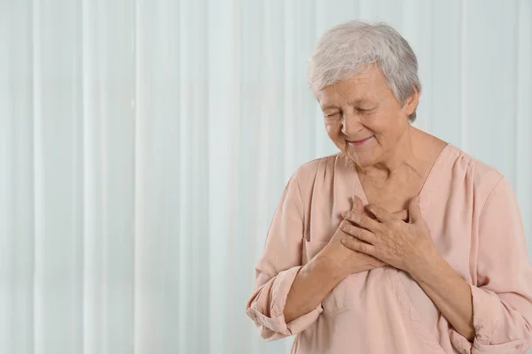 Tacksam Senior Kvinna Med Händerna Bröstet Mot Ljus Bakgrund Plats — Stockfoto