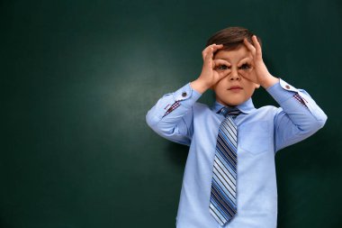 Funny little child near chalkboard, space for text. First time at school