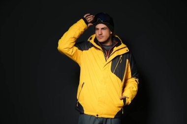 Siyah arka planda şık kış sporu giysileri giyen bir adam.