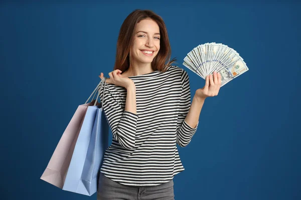 Glückliche Junge Frau Mit Bargeld Und Einkaufstaschen Auf Blauem Hintergrund — Stockfoto