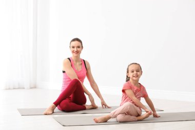 Küçük kızı olan genç bir anne evde yoga yapıyor.