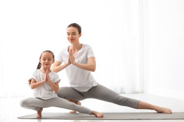 Küçük kızı olan genç bir anne evde yoga yapıyor.