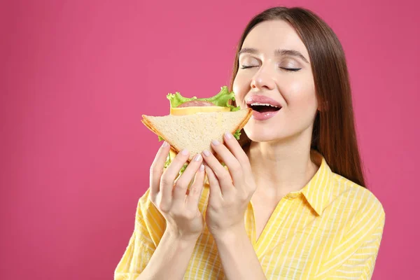 Jovem Mulher Comendo Saboroso Sanduíche Fundo Rosa — Fotografia de Stock