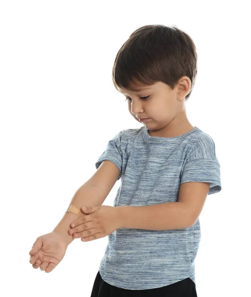 Little boy with sticking plaster on arm against white background